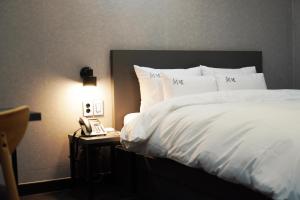a bed with white sheets and a phone on a table at Hotel Cheongdam in Mokpo