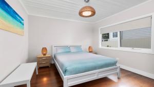 een witte slaapkamer met een bed en een raam bij Salt Air Currarong Beach house in Currarong