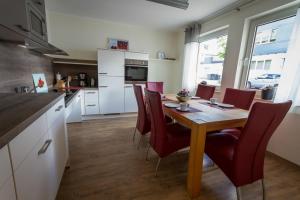 a kitchen with a wooden table and red chairs at Ferienwohnungen Haus Cramer in Winterberg