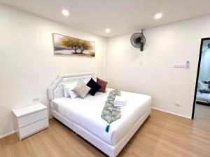 a white bedroom with a white bed with a picture on the wall at Peace Homestay Hat Yai in Hat Yai