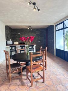 une table à manger et des chaises avec un vase de fleurs dans l'établissement Villa Malaquita, à San Miguel de Allende