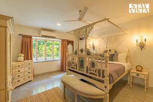 a bedroom with a canopy bed and a window at StayVista at A Portuguese Tale - Pool, Bar & BBQ in Assagao +48 photos