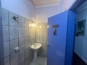 a bathroom with a toilet and a sink and a blue door at Hotel Palace Econômico in Goiânia