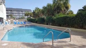 a large swimming pool with blue chairs and a building at Bluewater Resort 502 in Myrtle Beach