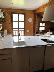 a kitchen with a sink and a clock on the wall at Fleurs Des Prés in Les Villards-sur-Thônes