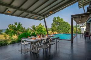a patio with a table and chairs and a swimming pool at SaffronStays Sommeliers Choice in Gangāpur