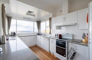 a kitchen with white cabinets and a large window at Dalia's Blue Mountain Retreat in Katoomba