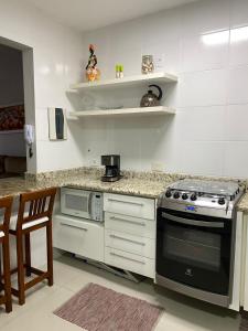 a kitchen with a stove and a microwave at Apto todo equipado em Caiobá há 50m do mar in Matinhos