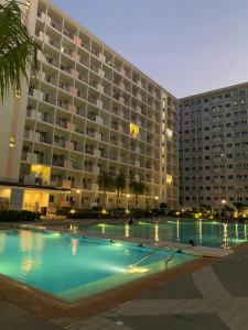 a large building with a swimming pool in front of it at Jazz Cozy Abode in Manila