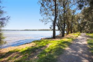 a path next to a body of water with trees at Sanctuary Bliss in Sanctuary Point