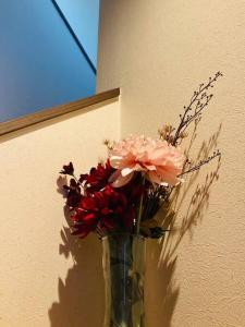 eine Vase voller Blumen neben einer Wand in der Unterkunft ぷらむならまち Sakura邸 in Nara