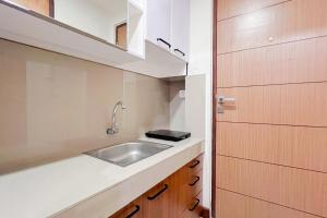 PampangにあるScenic Studio Apartment at Vida View Makassar By Travelioの小さなキッチン(シンク、木製キャビネット付)