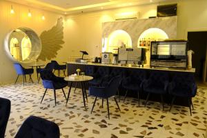a restaurant with blue chairs and a counter and tables at غسق الليل 2 للشقق المخدومة in Al Qarāḩīn