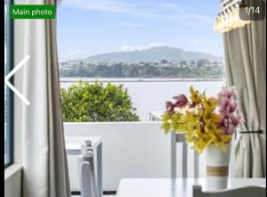 a vase of flowers on a table in front of a window at Tauranga Harbour View in Tauranga