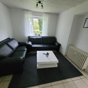 a living room with a black leather couch and a coffee table at Ferienwohnung Mendig in Mendig