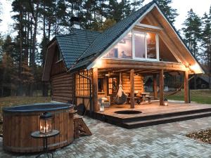 a small log cabin with a large deck and a woman at "Gaujmale" sauna house in nature in Laukbeitini