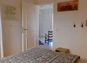 a bedroom with a bed and a room with a chair at Ferienhaus an der Buche "Gartenblick" in Neue Tiefe Fehmarn