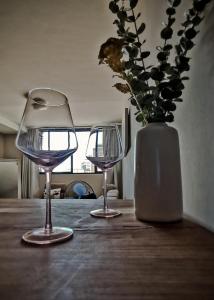 deux verres à vin assis sur une table en bois avec un vase dans l'établissement Windhoek Kalahari Haven, à Windhoek
