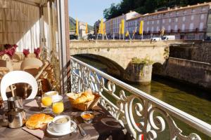 a table with food on a balcony next to a bridge at Hôtel Le Lons in Foix