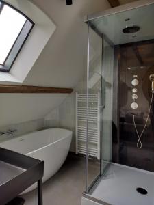 un baño con bañera y ducha de cristal en B&B 'Hof Baaiweg' met Barrelsauna, en Zoutelande