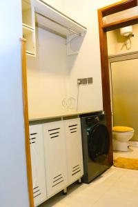 un bagno con lavatrice e asciugatrice accanto a servizi igienici di FirstChoice apartments Kampala a Kampala