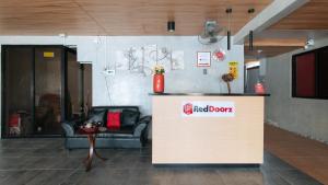 マニラにあるRedDoorz near Christ the King Medical Centerの赤いドアの看板とテーブルが置かれた待合室