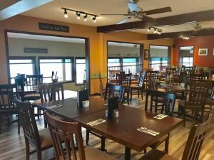 a dining room with tables and chairs and windows at Auberge Bay Wind Suites in Chéticamp