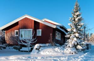 a red house with a christmas tree in the snow at Långänge Logi in Tandsbyn