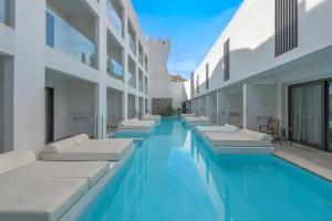 a swimming pool with lounge chairs in a building at Lindos Royal Resort in Líndos