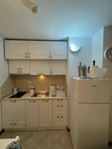 a kitchen with white cabinets and a sink and a refrigerator at Heritage in Oasis Resort Lozenets in Lozenets +21 photos