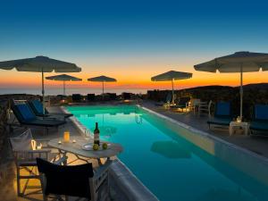 una piscina con sedie e un tavolo con una bottiglia di vino di Lithia Villas a Chora Folegandros