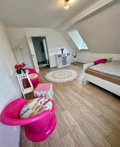 a living room with a bed and a pink chair at Ferienwohnungen Dörte & Stella Hof Saale in Hof +16 photos