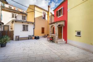 a courtyard between two buildings with a red yellow and white at Holiday Home Doda in Fažana - 100 m from the Sea in Fažana +24 photos
