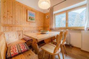 a dining room with a wooden table and chairs at Dolomitissime Holiday Homes Marmolada in Rocca Pietore