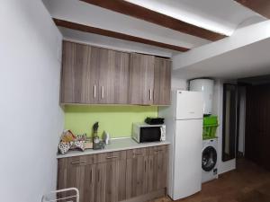 eine Küche mit Holzschränken und einem weißen Kühlschrank in der Unterkunft Casa Valentina y La buhardilla in Salvacañete