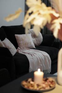 una vela en una mesa junto a un sofá negro en Vista apartment2, en Choszczówka