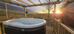 a jacuzzi tub on a deck with the sunset at The Fells - Campsie Luxury Pods with hot tub in Glasgow