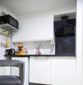a white kitchen with white cabinets and a sink at Le Relax Place - Metro 5 Bobigny in Bobigny