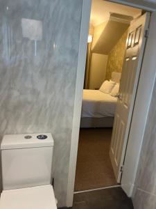 a bathroom with a toilet and a room with a bed at Ravenswood Guest House in Stirling +119 photos