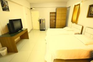 ein Hotelzimmer mit 2 Betten und einem TV in der Unterkunft At Home Phetkasem in Bangkok