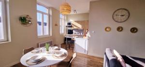 a living room with a table and a clock on the wall at Sunny - Hypercentre - Fibre in Sin-le-Noble