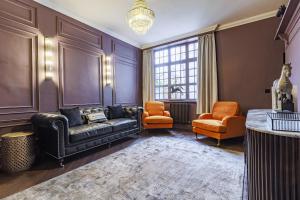 a living room with a leather couch and two orange chairs at The Seven Chester in Chester