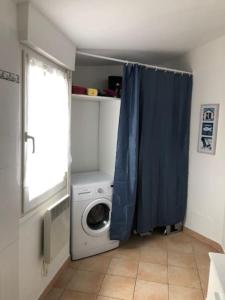 グリュイッサンにあるLe Soleil Levantの洗濯機と青いカーテンのある洗濯室