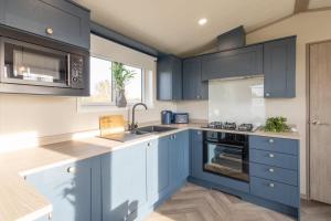 a kitchen with blue cabinets and a sink at Host & Stay - Riverwood, Ashdown Retreat in Pickering