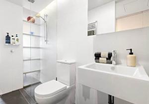 a white bathroom with a toilet and a sink at Nishi-Execs Couples and family retreat in Canberra