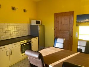 a kitchen with a wooden table and a refrigerator at Ferienhäuser Weitblick in Gilten
