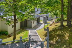 a house with a staircase leading to a yard with trees at SugarBear- Pool, AC, Sauna, Gym, Tennis in Killington