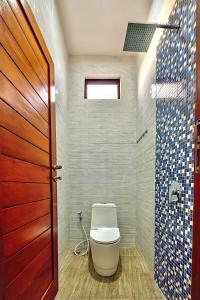 a bathroom with a toilet and a wooden door at Sleep Slept Dormitory in Canggu