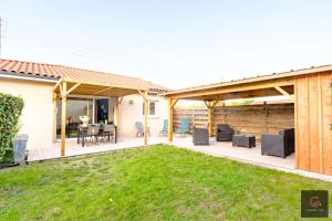 a patio with a table and chairs in a yard at Biscarrosse Bourg Maison tout confort en centre ville in Biscarrosse