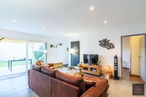 a living room with a brown couch and a television at Biscarrosse Bourg Maison tout confort en centre ville in Biscarrosse